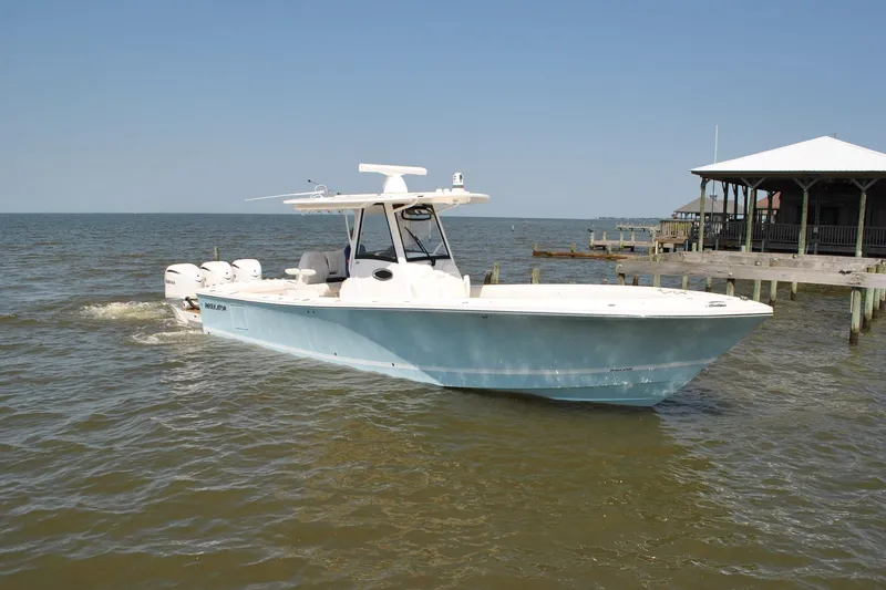 Slide: The Image of 2025 Regulator 34 Center Console boat cruising near a dock on a sunny day. - 21