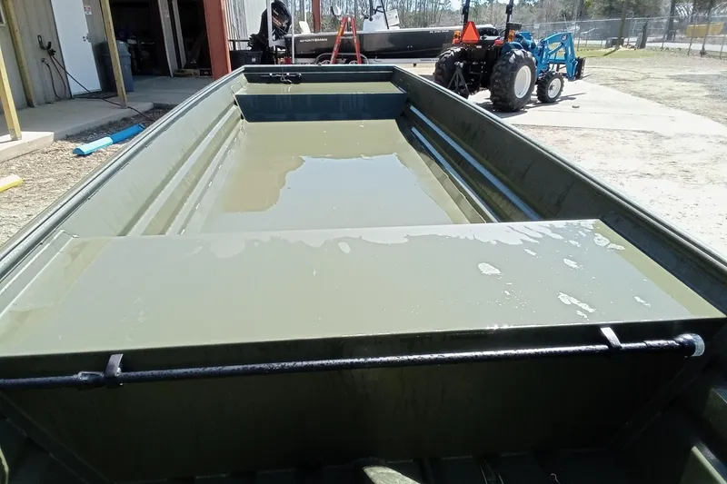 Slide: The Image of 2025 Alweld 1542 Flat Marsh boat with water inside, parked near a tractor. - 11