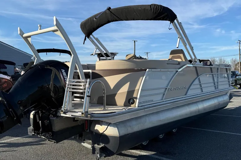 Slide: The Image of 2026 Berkshire 23RFX STS pontoon boat with outboard motor and canopy, parked outdoors. - 33