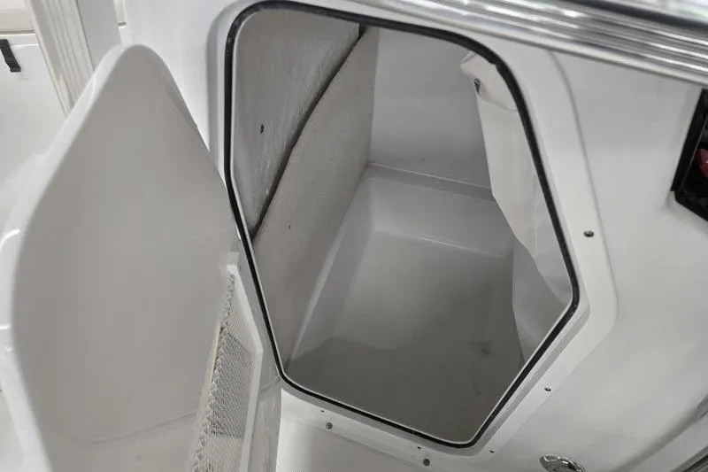 Slide: The Image of 2026 Sea Hunt Ultra 219 storage compartment, open door, white interior. - 16
