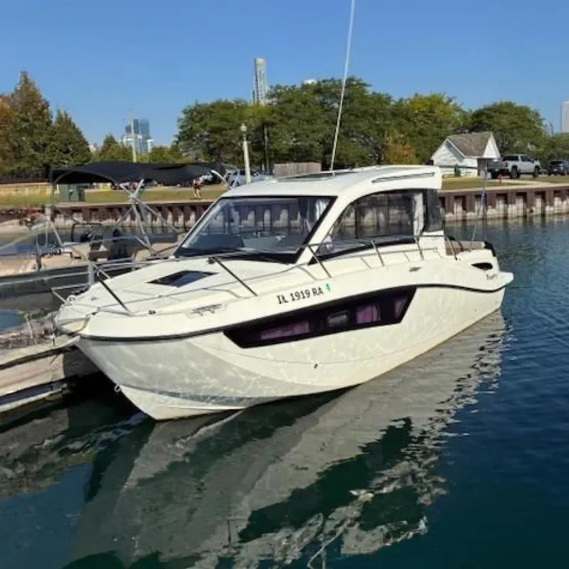 Slide: The Image of 2024 Bayliner Trophy T25 Explorer boat docked in a marina, surrounded by calm water. - 0