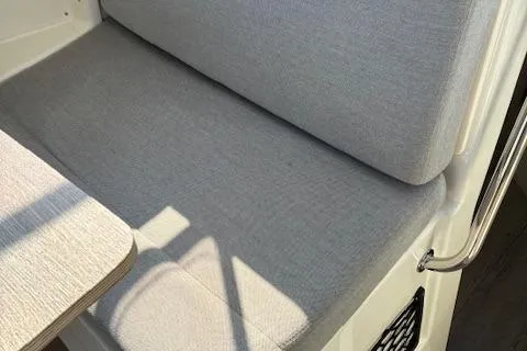 Slide: The Image of 2024 Bayliner Trophy T25 Explorer interior seating with light gray upholstery and adjacent table. - 12