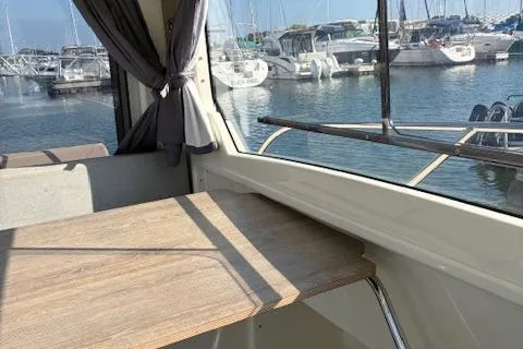 Slide: The Image of Interior view of 2024 Bayliner Trophy T25 Explorer, showcasing a wooden table and marina backdrop. - 21