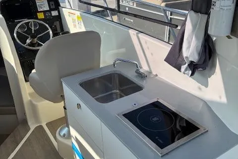 Slide: The Image of 2024 Bayliner Trophy T25 Explorer interior with helm, sink, and stove. - 24