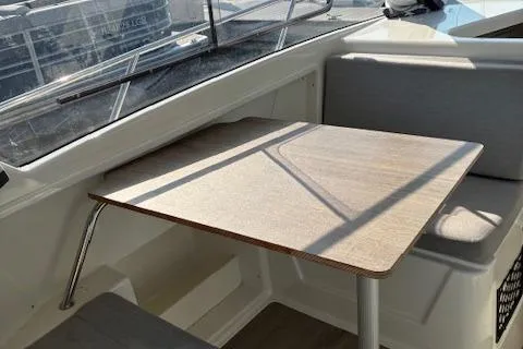 Slide: The Image of 2024 Bayliner Trophy T25 Explorer interior with wooden table and cushioned seating. - 25