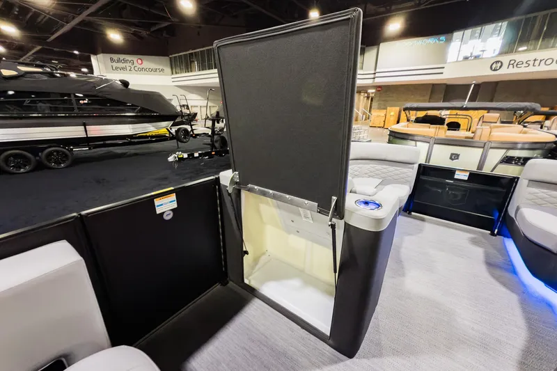 Slide: The Image of 2026 Godfrey Monaco 235 Split Bench interior with open storage compartment at a boat show. - 15