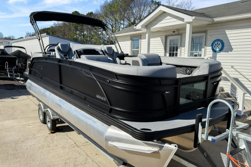 Slide: The Image of 2026 Godfrey Monaco 235 Split Bench pontoon boat on trailer, parked near a building. - 27