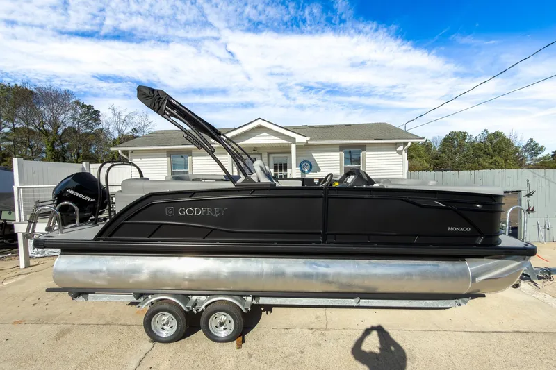 Slide: The Image of 2026 Godfrey Monaco 235 Split Bench pontoon boat on trailer, parked in driveway. - 28
