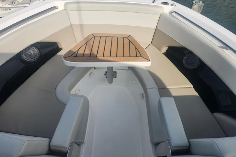Slide: The Image of 2021 Boston Whaler 280 Vantage boat interior with cushioned seating and wooden table. - 16
