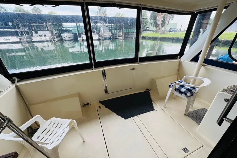 Slide: The Image of Interior of 1985 Bluewater 51 Coastal Cruiser with chairs and marina view. - 11
