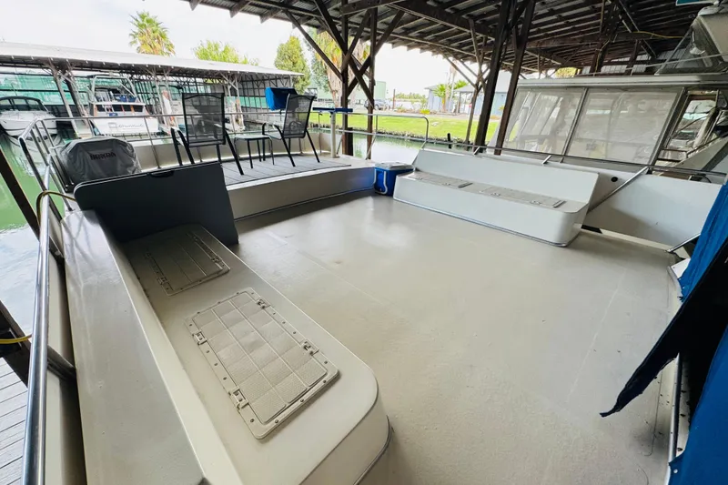 Slide: The Image of 1985 Bluewater 51 Coastal Cruiser boat deck under covered dock, featuring seating and chairs. - 15