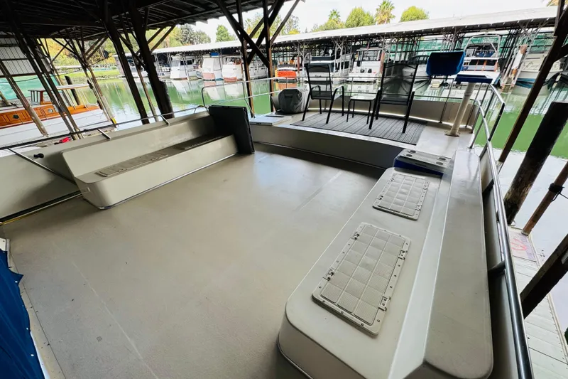 Slide: The Image of 1985 Bluewater 51 Coastal Cruiser docked, featuring spacious deck with seating and chairs. - 17