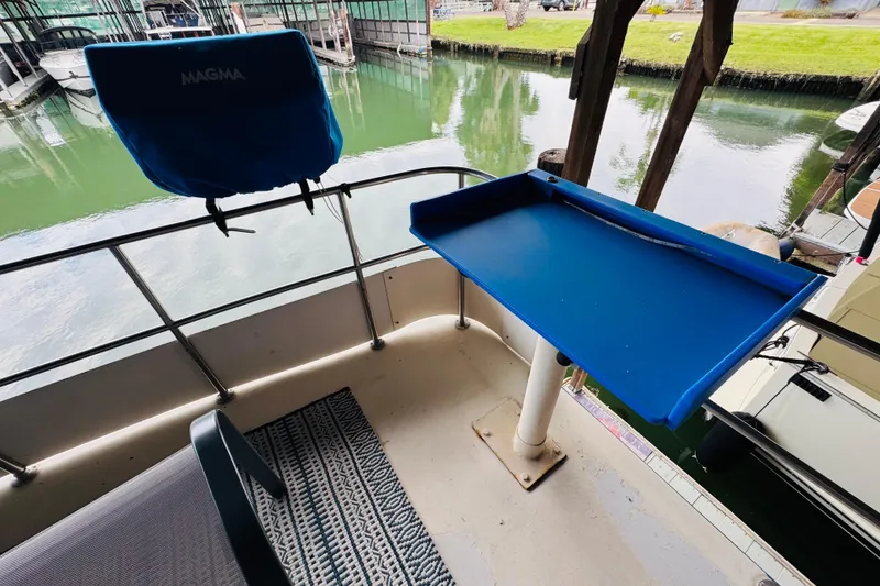 Slide: The Image of 1985 Bluewater 51 Coastal Cruiser deck with blue table and chair, docked by calm water. - 19