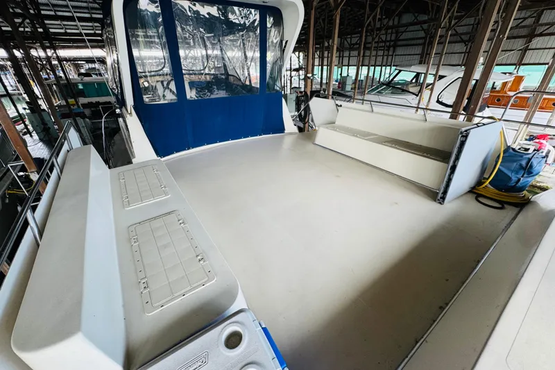 Slide: The Image of 1985 Bluewater 51 Coastal Cruiser boat deck in marina, featuring spacious seating and storage. - 21