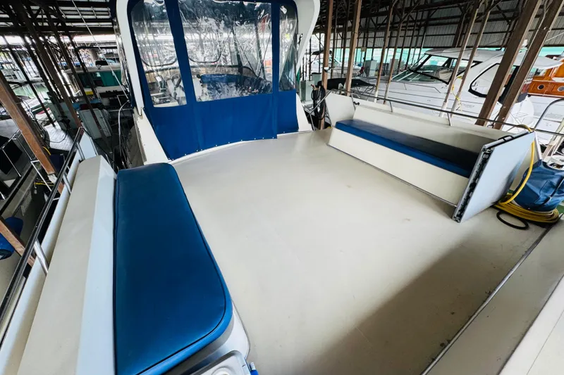 Slide: The Image of 1985 Bluewater 51 Coastal Cruiser deck with blue seating and canopy in marina. - 22