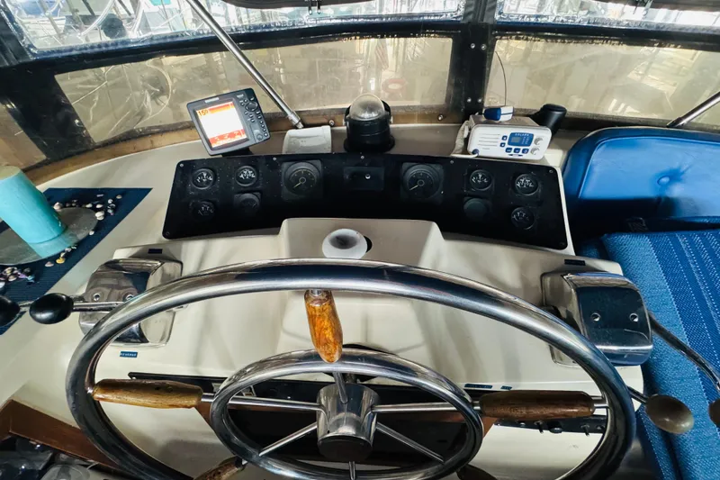 Slide: The Image of 1985 Bluewater 51 Coastal Cruiser helm with steering wheel and navigation instruments. - 26