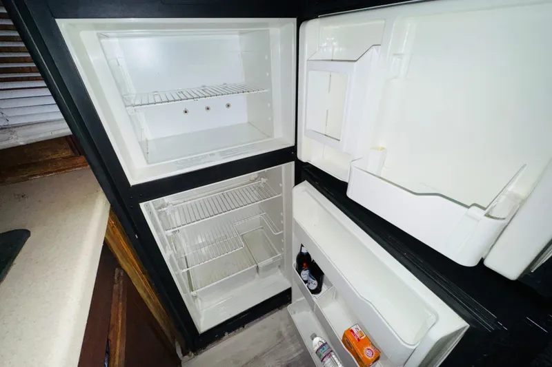 Slide: The Image of Open refrigerator inside 1985 Bluewater 51 Coastal Cruiser yacht, showing shelves and door storage. - 37
