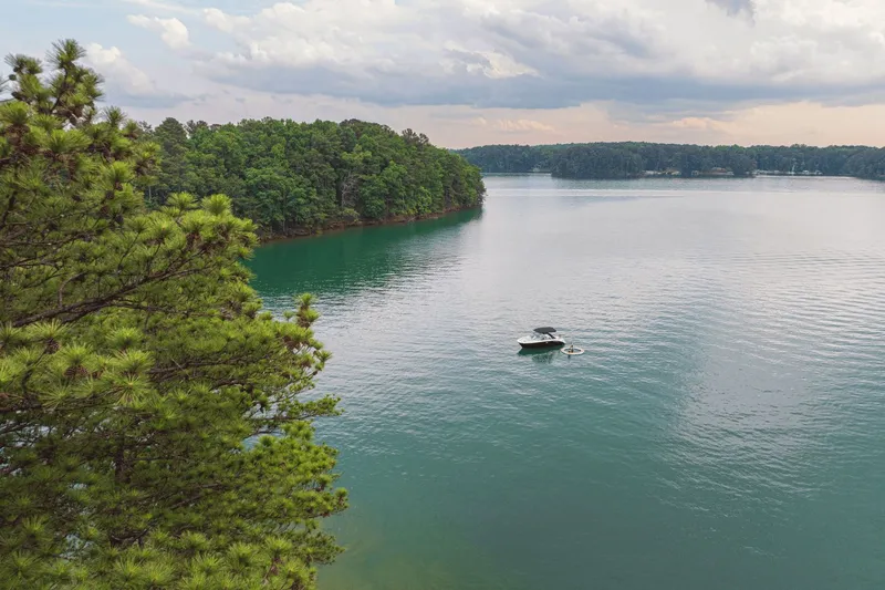 Slide: The Image of Sea Ray SDX 250 boat on tranquil lake surrounded by trees. - 12
