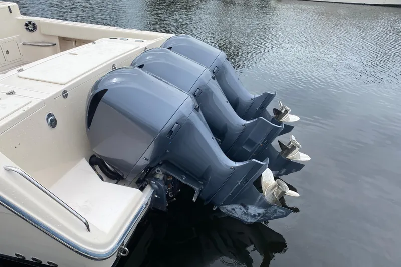 Slide: The Image of Triple outboard motors on a 2012 Grady-White Express 360 boat, docked on calm water. - 25