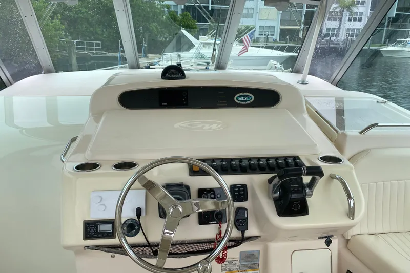 Slide: The Image of Grady-White Express 360 helm with steering wheel and controls, docked near other boats. - 7