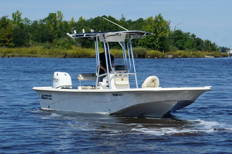 The Image of 2023 Carolina Skiff 21 LS boat cruising on a scenic river with lush greenery. - 0