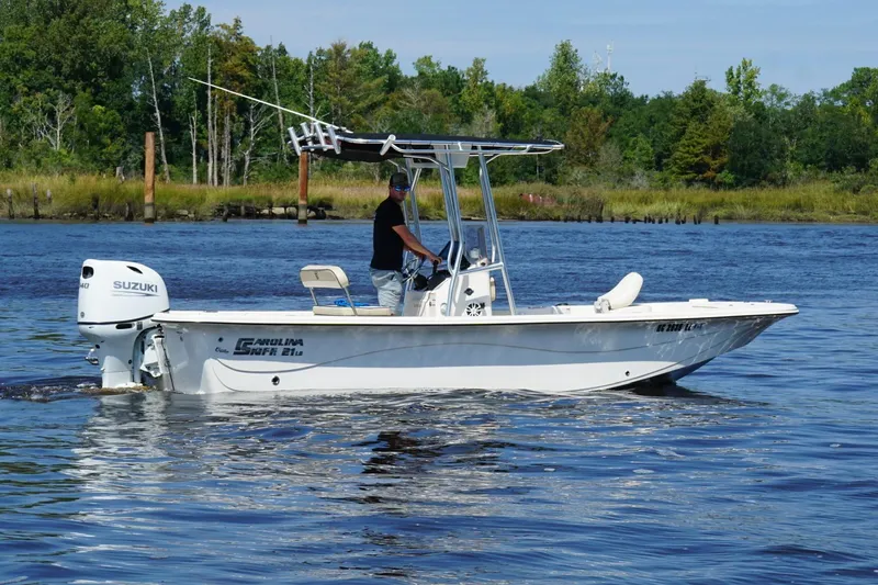 Slide: The Image of 2023 Carolina Skiff 21 LS boat on water, featuring Suzuki outboard motor. - 2