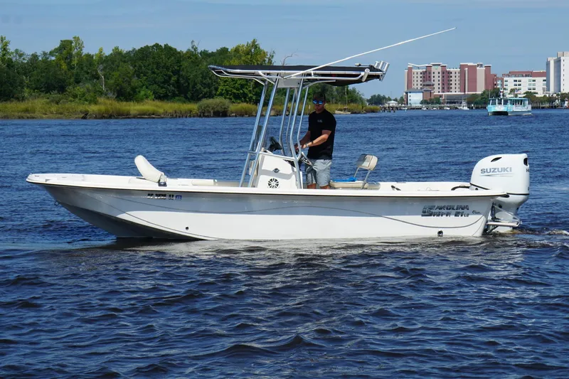 Slide: The Image of 2023 Carolina Skiff 21 LS boat cruising on a river with a Suzuki outboard motor. - 21