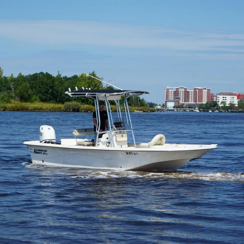 Slide: The Image of 2023 Carolina Skiff 21 LS boat cruising on a river with a cityscape background. - 4