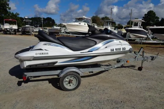 The Image of 2004 Yamaha WaveRunner FX Cruiser on trailer, parked in a boatyard under a cloudy sky. - 1