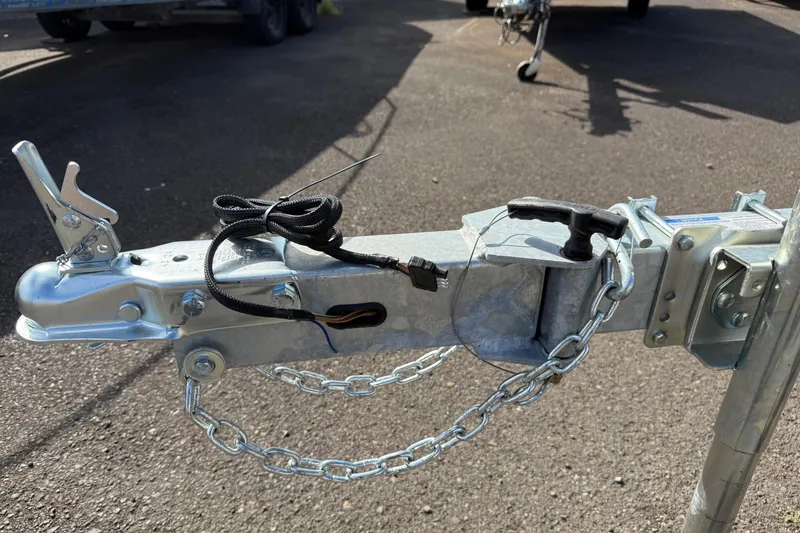 Slide: The Image of Trailer hitch of a 2026 Fish Rite Angler 18 boat, featuring safety chains and wiring. - 22