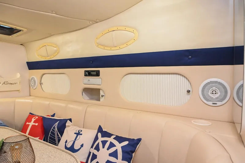 Slide: The Image of Interior of 2000 Rinker Fiesta Vee 330 with nautical-themed cushions and beige seating. - 26