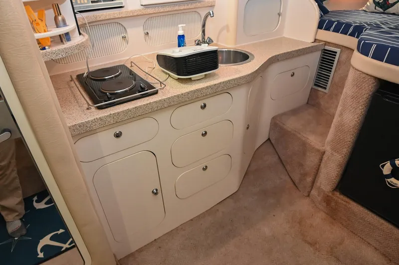 Slide: The Image of Compact kitchen area in a 2000 Rinker Fiesta Vee 330 boat, featuring a sink and stove. - 28