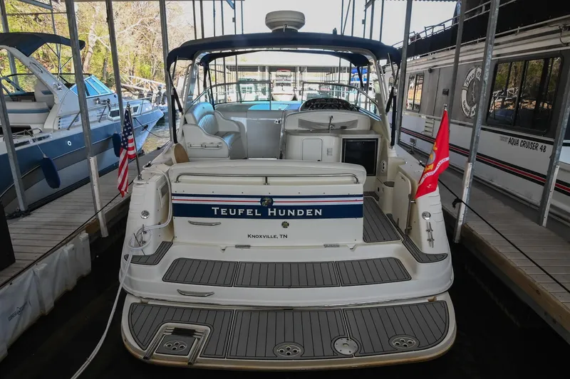 Slide: The Image of 2000 Rinker Fiesta Vee 330 boat docked, rear view with flags and seating area. - 3