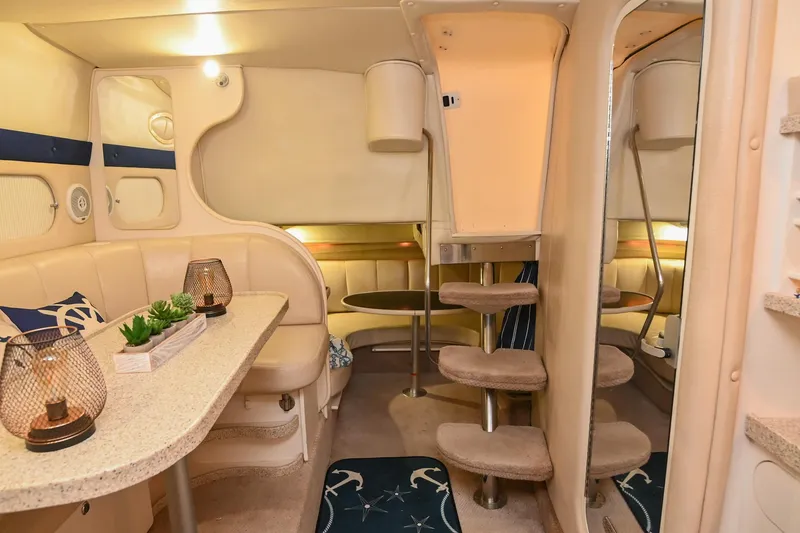 Slide: The Image of 2000 Rinker Fiesta Vee 330 interior with cozy seating, table, and carpeted stairs. - 33