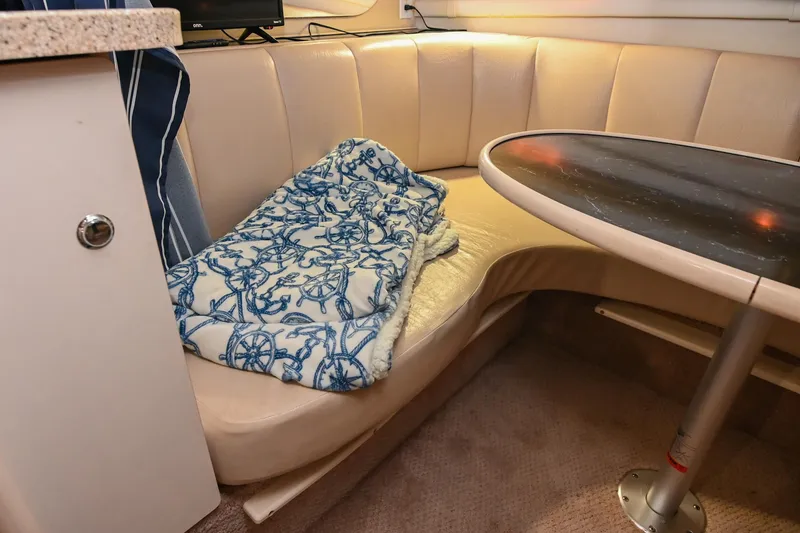 Slide: The Image of Interior of 2000 Rinker Fiesta Vee 330 with cozy seating and nautical-themed blanket. - 35