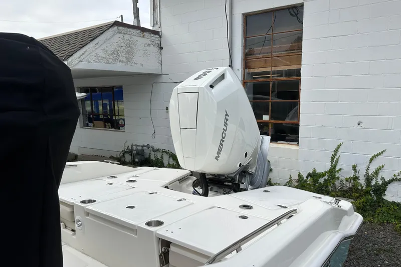 Slide: The Image of 2026 Boston Whaler 250 Dauntless with Mercury outboard engine, docked near a building. - 2