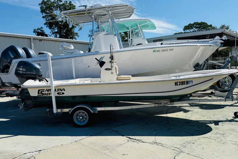 Slide: The Image of 2019 Carolina Skiff JV17CC boat on trailer, parked outdoors under clear blue sky. - 9