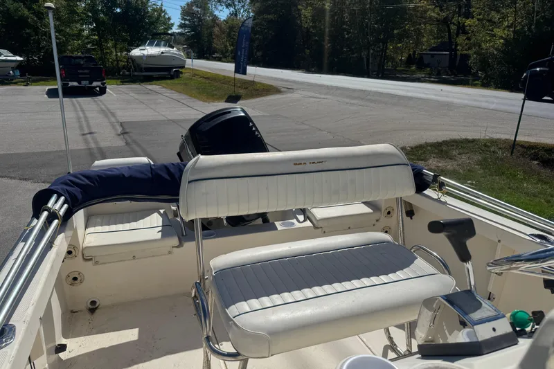 Slide: The Image of 2002 Seahunt Triton 202 boat interior with seating and controls, parked near a road. - 11