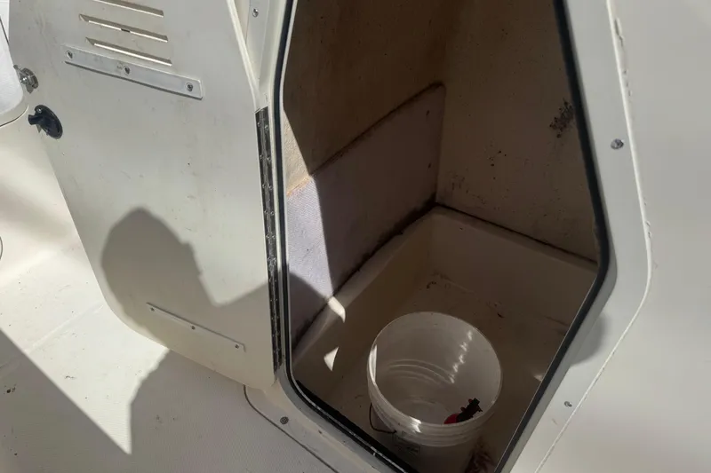 Slide: The Image of Open storage compartment on 2002 Seahunt Triton 202 boat with a white bucket inside. - 13