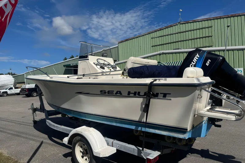 Slide: The Image of 2002 Seahunt Triton 202 boat on trailer, parked outdoors under blue sky. - 2