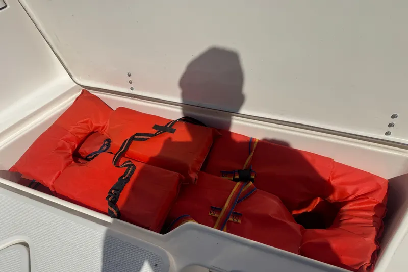 Slide: The Image of Red life jackets stored in a compartment of a 2002 Seahunt Triton 202 boat. - 5