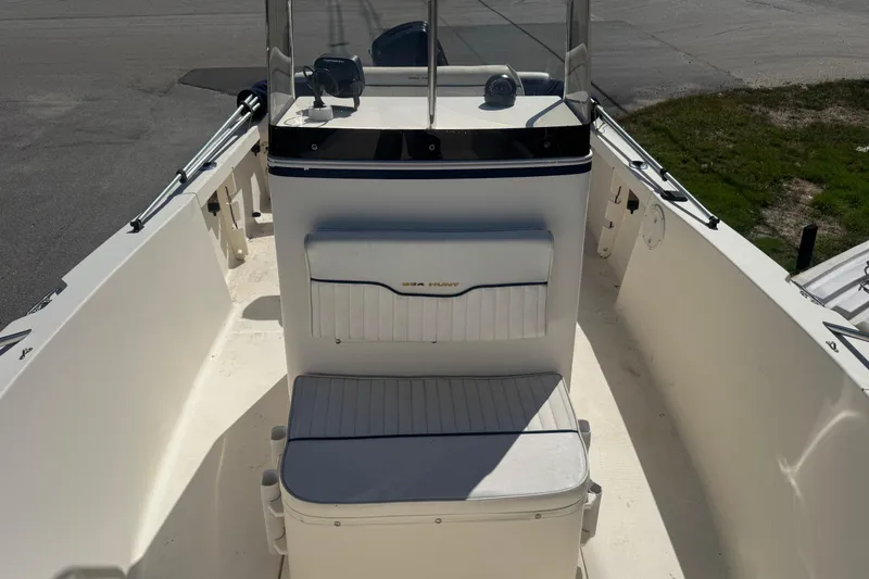 Slide: The Image of 2002 Seahunt Triton 202 boat interior with seating and console, docked on a sunny day. - 7