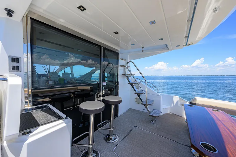 Slide: The Image of 2018 Cruisers 60 Cantius Fly yacht deck with bar stools and ocean view. - 11