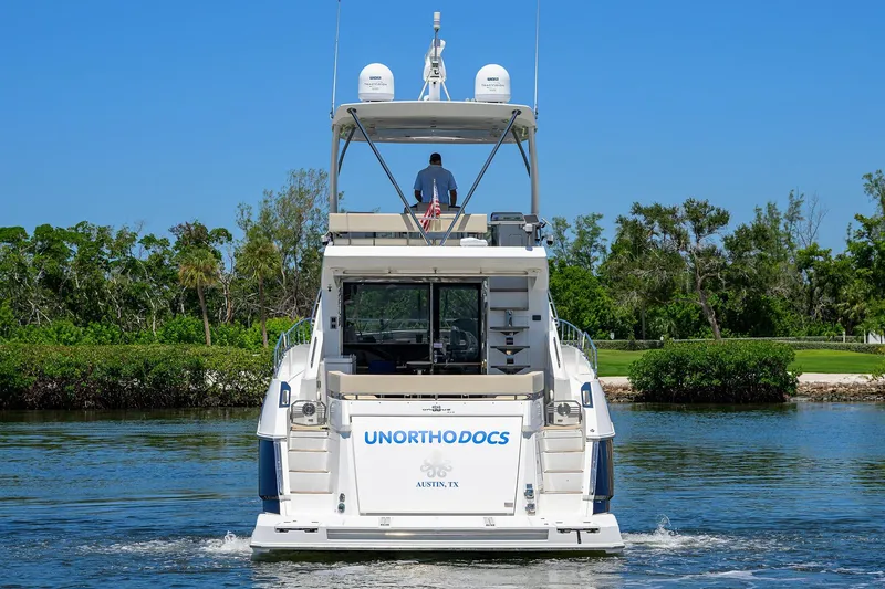 Slide: The Image of 2018 Cruisers 60 Cantius Fly yacht on water, lush greenery in background. - 5
