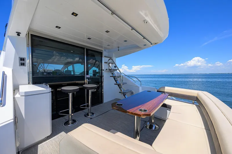 Slide: The Image of 2018 Cruisers 60 Cantius Fly yacht deck with seating, table, and ocean view. - 12