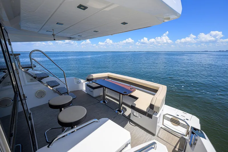 Slide: The Image of 2018 Cruisers 60 Cantius Fly yacht deck with seating, table, and ocean view. - 13