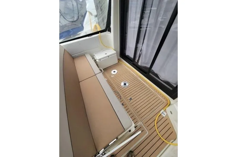 Slide: The Image of 2024 Bayliner Trophy T29 Explorer interior with tan seating and wood-style flooring. - 8