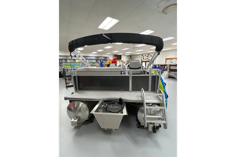 Slide: The Image of 2025 South Bay 16 FC SE pontoon boat in showroom, rear view with ladder and canopy. - 15