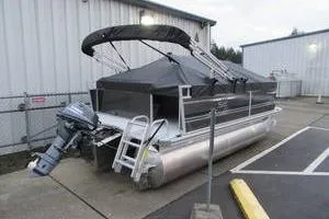 Slide: The Image of 2025 South Bay 16 FC SE pontoon boat parked near industrial building. - 2