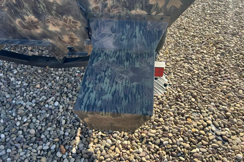Slide: The Image of Camouflage-patterned 2025 Crestliner 1660 Retriever FCC boat detail on gravel surface. - 3